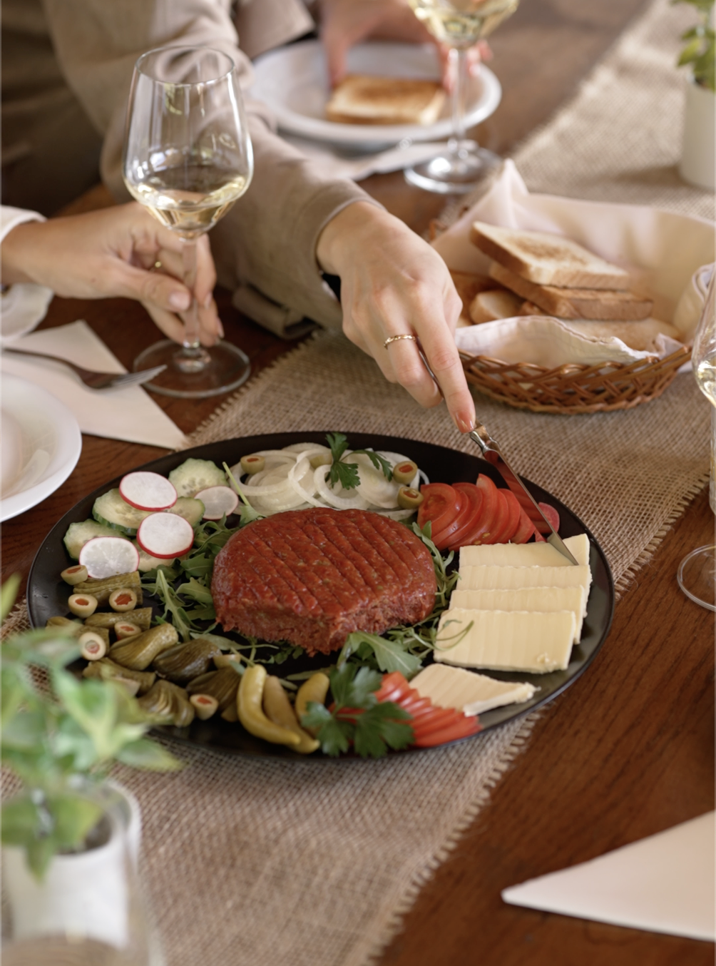 Predjed z domačo tartare, zelenjavo in sirom na pogrnjeni mizi